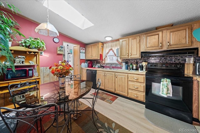 kitchen featuring lofted ceiling with skylight, light wood-style flooring, under cabinet range hood, light countertops, and black appliances