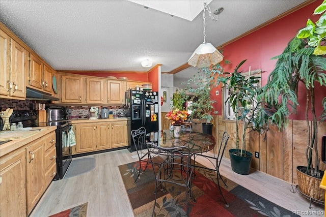 kitchen featuring tasteful backsplash, light wood-style flooring, under cabinet range hood, light countertops, and black appliances