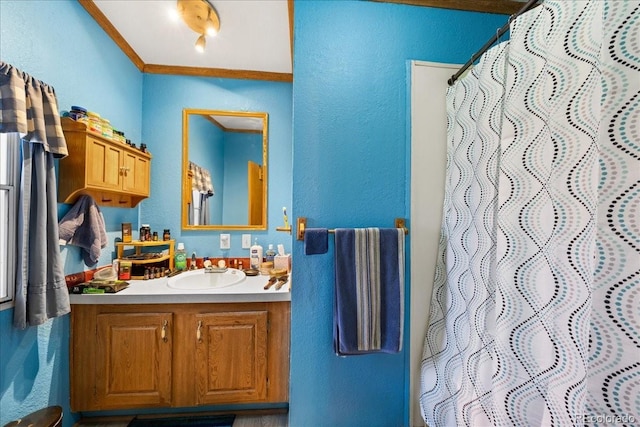 full bathroom featuring a textured wall, ornamental molding, vanity, and a shower with curtain