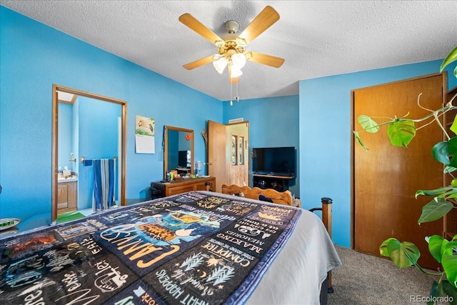 carpeted bedroom featuring a textured ceiling, ensuite bath, and a ceiling fan