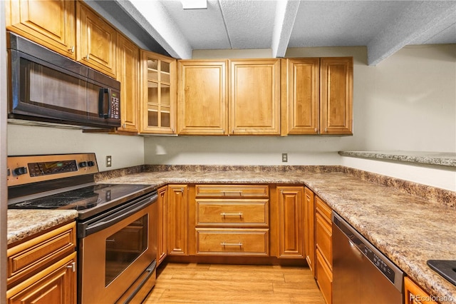 kitchen featuring appliances with stainless steel finishes, light wood-type flooring, brown cabinetry, and glass insert cabinets