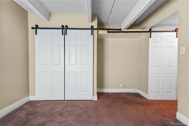 interior space featuring carpet floors, a barn door, and beam ceiling