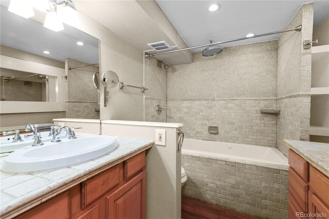 bathroom with toilet, recessed lighting, visible vents, vanity, and tiled shower / bath