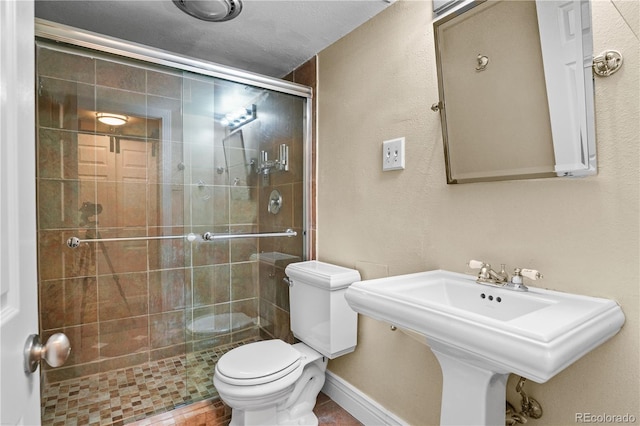 full bath with a sink, a shower stall, toilet, and baseboards