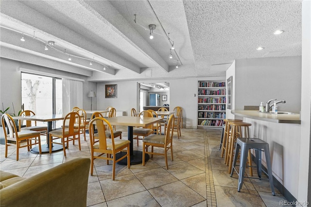 dining space featuring baseboards, a textured ceiling, track lighting, and light tile patterned floors