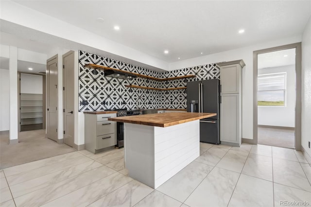 kitchen with wooden counters, high end black refrigerator, stainless steel electric stove, gray cabinetry, and recessed lighting