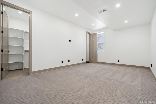 unfurnished bedroom featuring recessed lighting, light carpet, baseboards, and a spacious closet