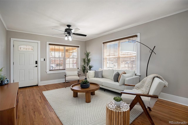 living room featuring light wood-style floors, crown molding, baseboards, and ceiling fan