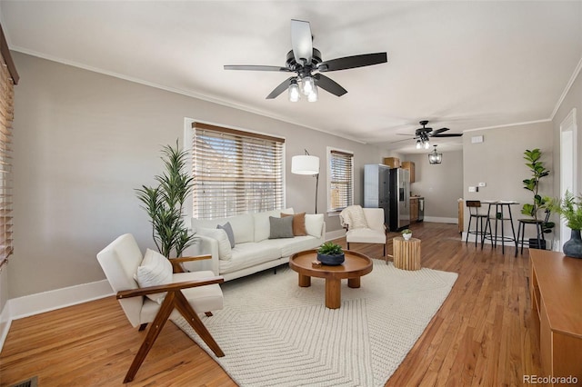 living room with a ceiling fan, baseboards, ornamental molding, and wood finished floors