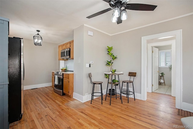 kitchen with stainless steel appliances, baseboards, light wood-style floors, light countertops, and crown molding