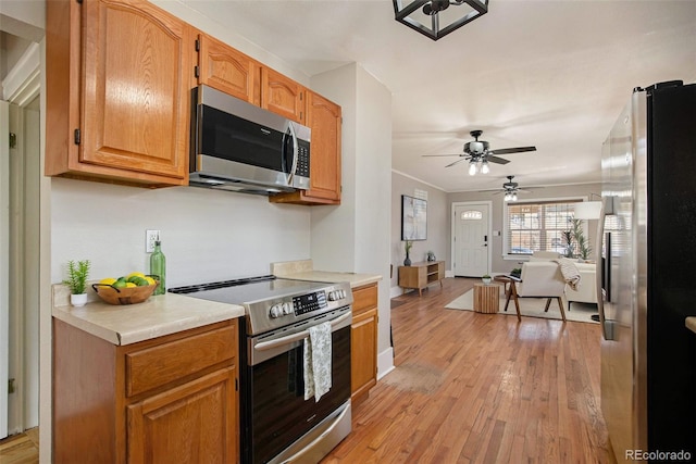 kitchen with light wood-style flooring, stainless steel appliances, baseboards, light countertops, and brown cabinets