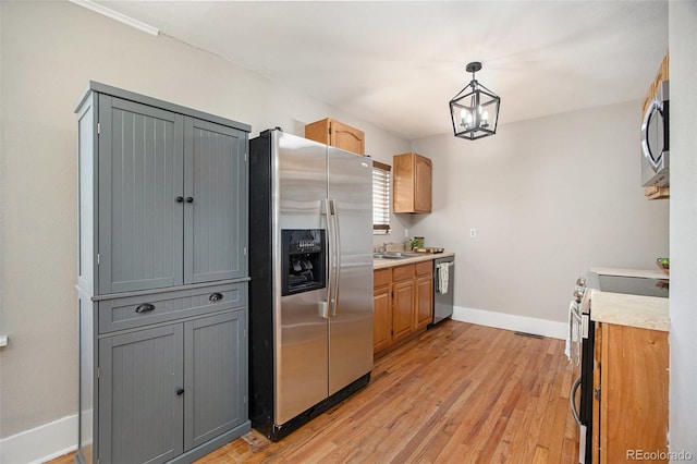 kitchen with stainless steel appliances, gray cabinets, light countertops, and decorative light fixtures