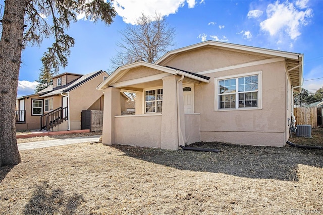 view of front facade with central AC, fence, and stucco siding