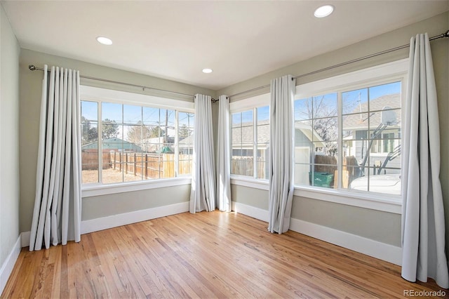 unfurnished room with light wood-style floors, plenty of natural light, and baseboards