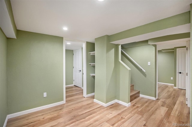 finished basement with light wood-style flooring, baseboards, and stairs