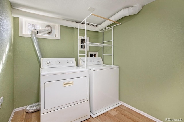 clothes washing area featuring laundry area, light wood-type flooring, independent washer and dryer, and baseboards