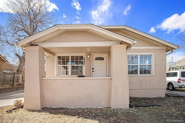 view of front facade featuring a porch, fence, and stucco siding