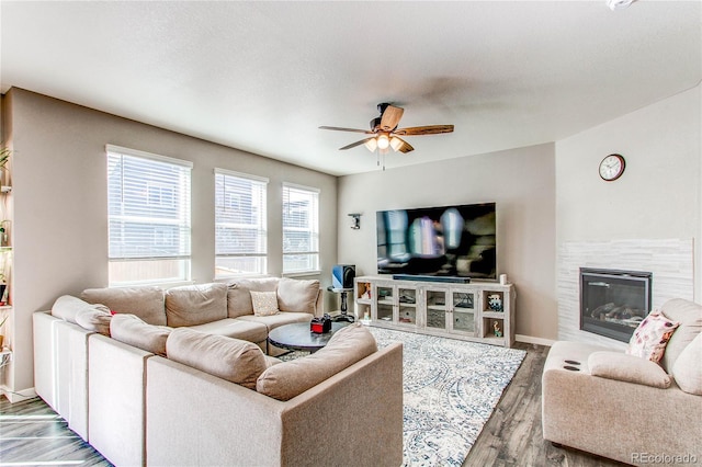 living area featuring a ceiling fan, wood finished floors, baseboards, and a tile fireplace