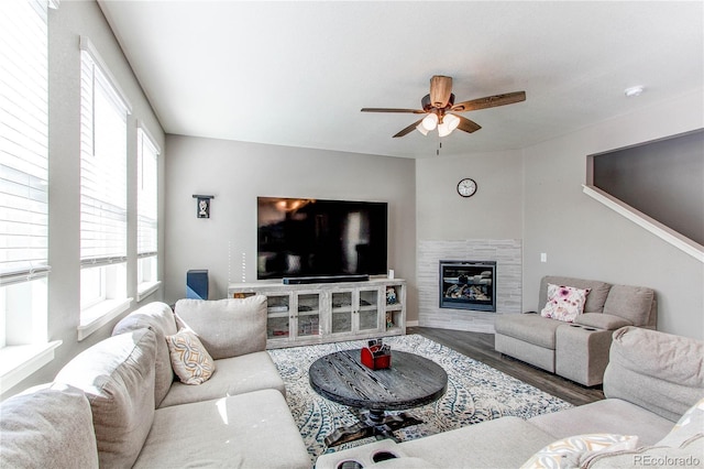 living area with wood finished floors, a tile fireplace, and ceiling fan