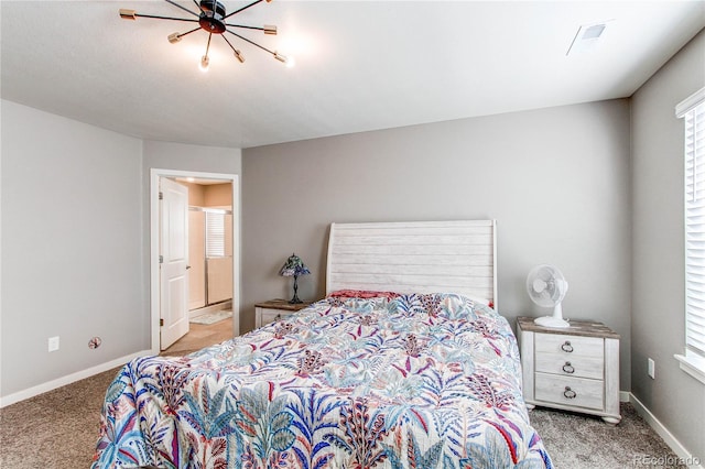 carpeted bedroom with ensuite bath and baseboards