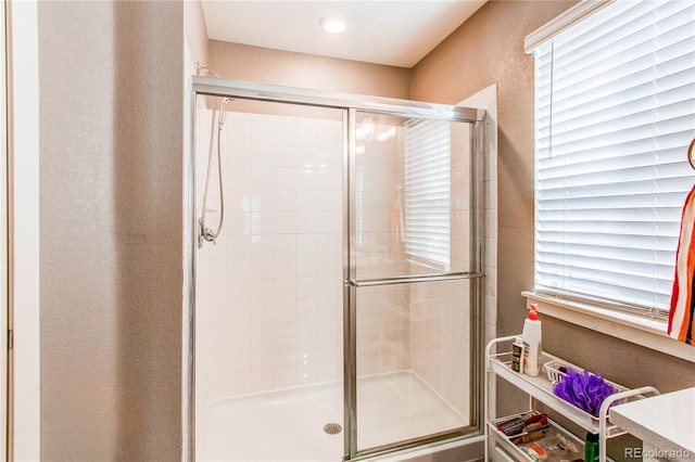 full bathroom with a shower stall and a textured wall