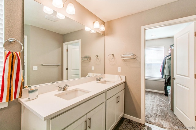 full bath featuring double vanity, baseboards, and a sink