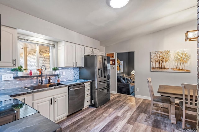 kitchen featuring stainless steel appliances, decorative backsplash, a sink, and white cabinets