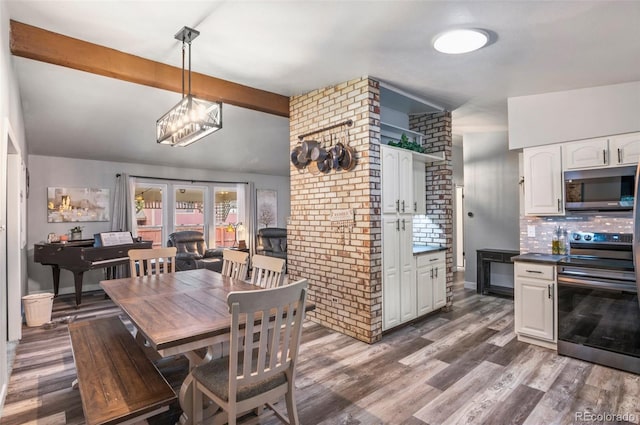 dining area featuring brick wall, beamed ceiling, and wood finished floors