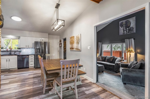 dining area with baseboards, vaulted ceiling, and wood finished floors