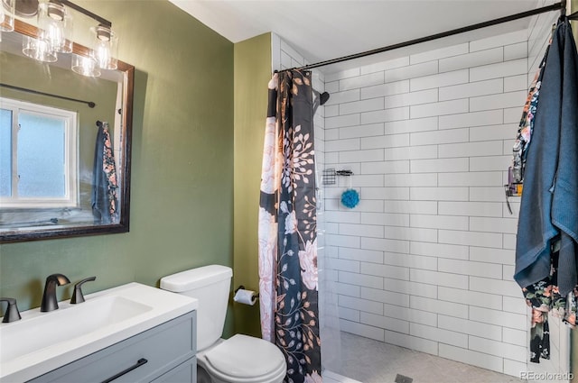 bathroom with toilet, tiled shower, and vanity