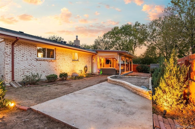 back of property featuring a patio area, a chimney, fence, and brick siding