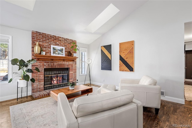 living room with lofted ceiling with skylight, a brick fireplace, and dark wood-type flooring