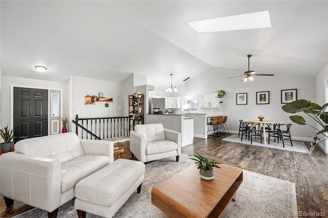 living room with hardwood / wood-style flooring, vaulted ceiling with skylight, and ceiling fan