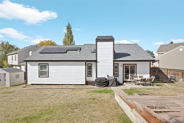 back of property with a patio area, a lawn, and a storage unit