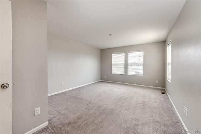 carpeted spare room featuring baseboards and visible vents