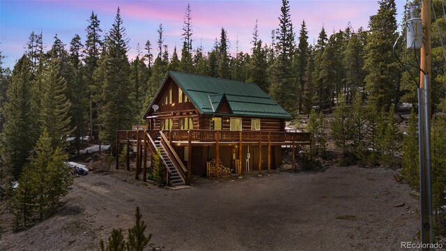 795 Zebulon St, Alma, CO 80420 - back of house at dusk featuring a deck, log siding, stairs, metal roof, and a forest view