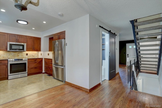 6844 S Broadway, Littleton, CO 80122 - kitchen with stainless steel appliances, a barn door, light wood finished floors, tasteful backsplash, and recessed lighting