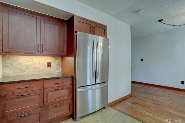 6844 S Broadway, Littleton, CO 80122 - kitchen featuring freestanding refrigerator, baseboards, backsplash, light wood-style flooring, and dark stone countertops