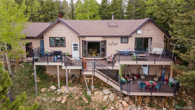 11094 Thomas Dr, Conifer, CO 80433 - back of house featuring a shingled roof, a wooden deck, outdoor dining space, and stairway