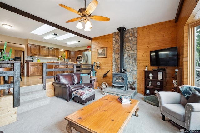 11094 Thomas Dr, Conifer, CO 80433 - living area with wood walls, light carpet, a wood stove, and a ceiling fan