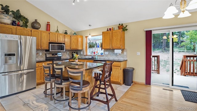 kitchen featuring decorative light fixtures, stainless steel appliances, decorative backsplash, and a center island