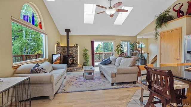 living room featuring high vaulted ceiling, light hardwood / wood-style flooring, a wood stove, and a wealth of natural light