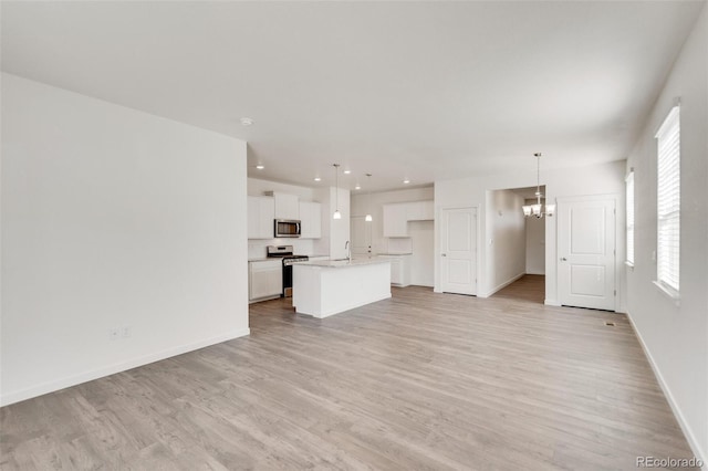 unfurnished living room with an inviting chandelier, sink, and light hardwood / wood-style floors