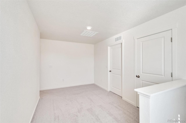 empty room featuring light carpet and a textured ceiling