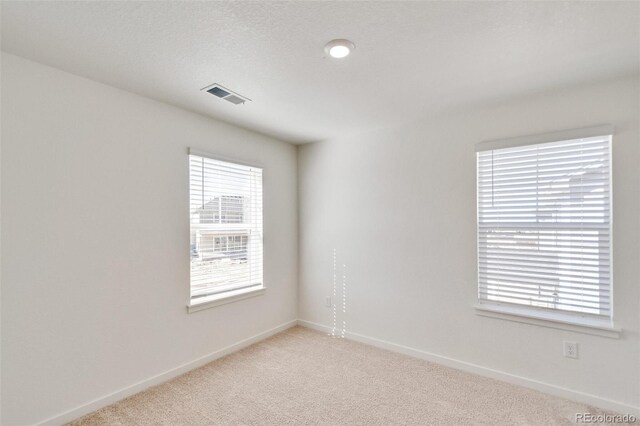 carpeted spare room with a textured ceiling