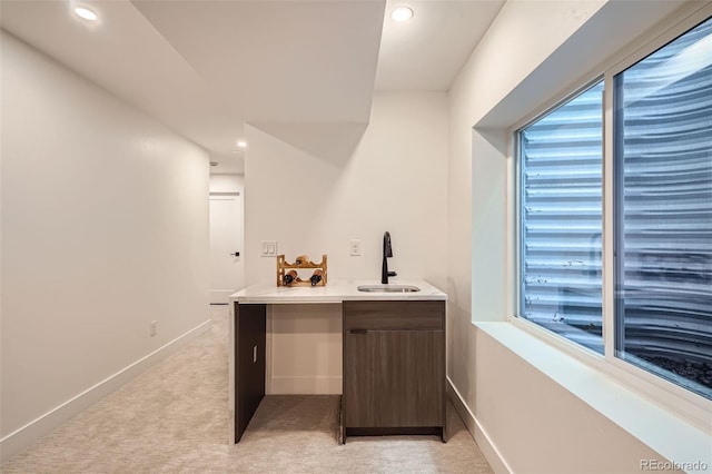 bar featuring sink, light colored carpet, and dark brown cabinets