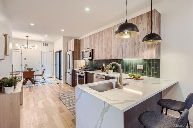 kitchen featuring sink, high end appliances, decorative light fixtures, and kitchen peninsula