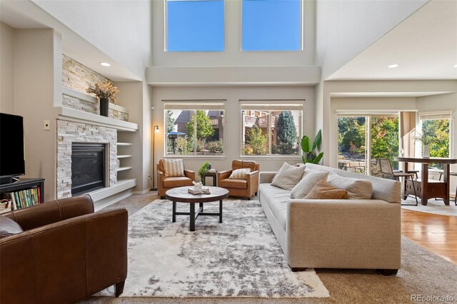 living room featuring a towering ceiling, plenty of natural light, and a fireplace