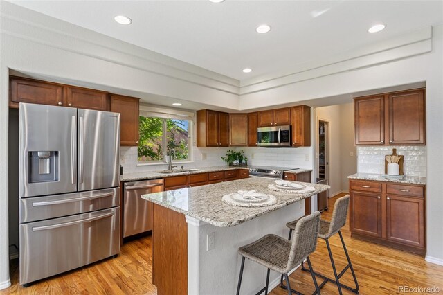 kitchen featuring light hardwood / wood-style floors, a breakfast bar area, stainless steel appliances, a center island, and sink