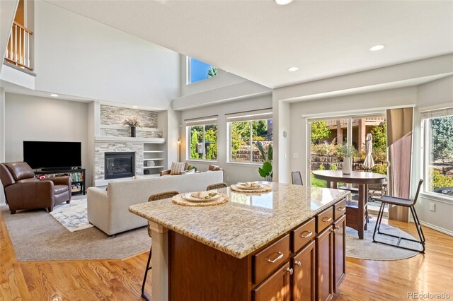 kitchen with light wood-type flooring, a high ceiling, a center island, and a fireplace